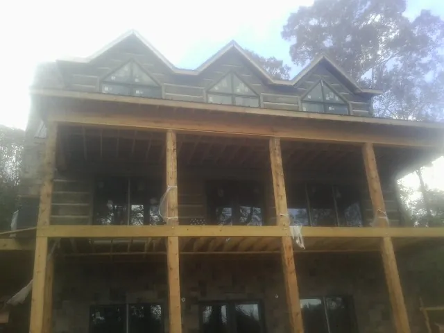 Dormers and porch framing on a large log home under construction — Roof Coating work by our crew in Raleigh