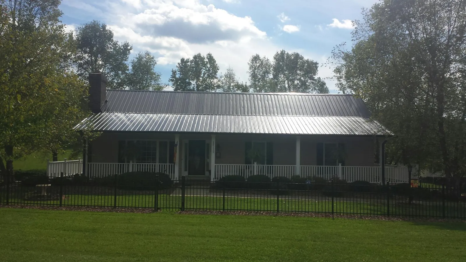 Gray metal roof on a brick ranch with a full width front porch — Gutter Guard Installation work by our crew in Raleigh